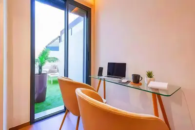 a room with a desk with a laptop and chairs at MAYA SUITES - Corniche Seaside in Casablanca