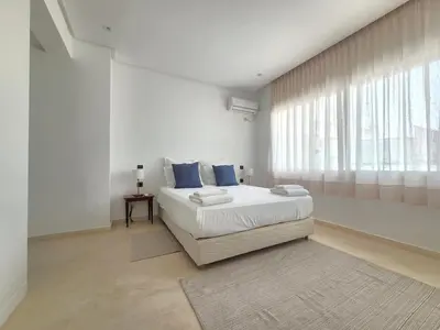 a white bedroom with a bed and a window at The Nineteen Racine by IB Signature - Stylish two-Bedroom flat - Wifi, Self Check-in, Day and Night Security, Terrace, free parking, close to all amenities in Casablanca