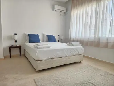 a white bedroom with a large bed with blue pillows at The Nineteen Racine by IB Signature - Stylish two-Bedroom flat - Wifi, Self Check-in, Day and Night Security, Terrace, free parking, close to all amenities in Casablanca