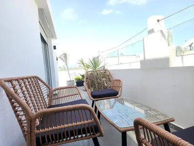 three wicker chairs and a glass table on a balcony at The Nineteen Racine by IB Signature - Stylish two-Bedroom flat - Wifi, Self Check-in, Day and Night Security, Terrace, free parking, close to all amenities in Casablanca