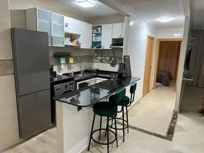 a kitchen with a refrigerator and a counter with stools at Appartement Haut standing in Mohammedia