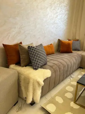 a couch with pillows on it in a living room at Les Flots Blancs - Appartement détente et bonheur côté mer in Bouznika