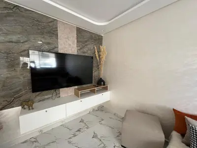 a living room with a flat screen tv on a wall at Les Flots Blancs - Appartement détente et bonheur côté mer in Bouznika