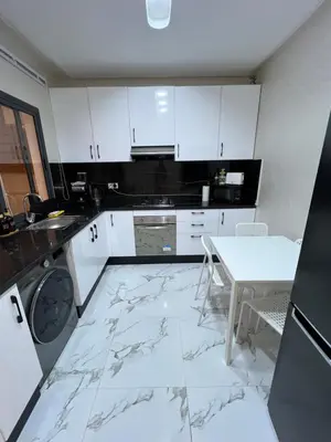 a kitchen with white cabinets and a marble floor at Les Flots Blancs - Appartement détente et bonheur côté mer in Bouznika