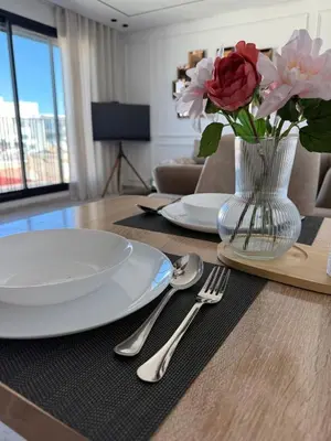 a table with plates and a vase of flowers on it at Metropoleparc luxury apparthotel in Casablanca