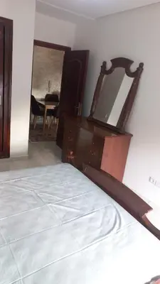 a bedroom with a bed with a dresser and a mirror at Appartement ville des roses in Mohammedia