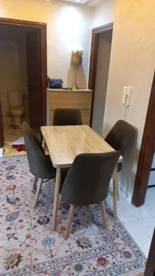 a dining room with a wooden table and chairs at Appartement ville des roses in Mohammedia