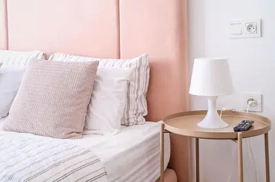 a bed with white pillows and a table with a lamp at Modern and cozy studio Close to CFC & Maarif in Casablanca