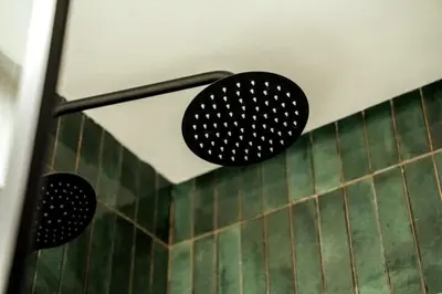 a bathroom with two black hooks on a green tiled wall at Résidence Pashmina in Maarif