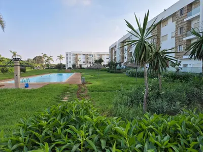 a resort with a pool and a palm tree at Appartement Baraa Havre de sérénité entre mer et nature à tamaris in Tamaris