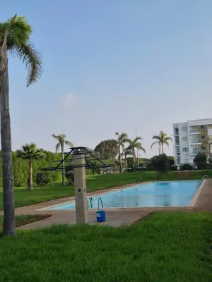 a swimming pool in a park with a palm tree at Appartement Baraa Havre de sérénité entre mer et nature à tamaris in Tamaris