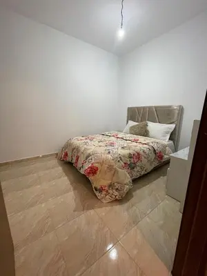 a bedroom with a bed with a comforter on it at High apartment in Oulad Hamida