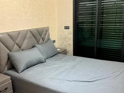 a bed with a gray pillow in a bedroom at Bel Appartement moderne et propre proche de l aéroport in Deroua