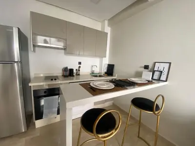 a kitchen with a counter with two chairs and a refrigerator at Cosy Maarif in Casablanca