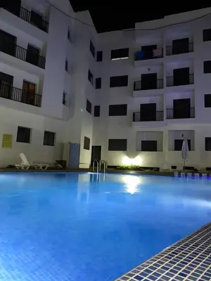 a large swimming pool in front of a building at Appartement Moderne avec Piscine in Bouznika