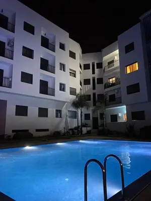 a swimming pool in front of a building at night at Appartement Moderne avec Piscine in Bouznika