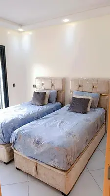 two beds sitting next to each other in a bedroom at Appartement Moderne avec Piscine in Bouznika