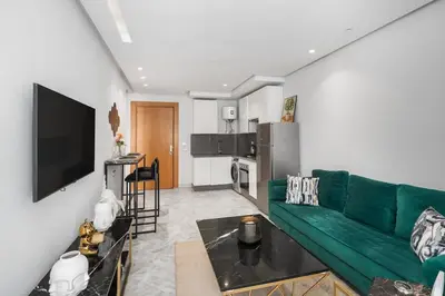 a living room with a green couch and a kitchen at Cozy studio on the Casablanca Ain Diab corniche in Casablanca