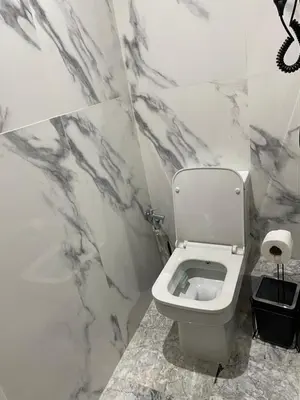 a bathroom with a white toilet and marble walls at Appartement neuf luxe OLM Aviation à Rabat in Rabat