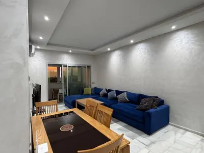 a living room with a blue couch and a table at Cozy apartment Sea view & Comfort in Mohammedia