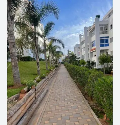 a brick pathway with palm trees and a building at Cozy apartment Sea view & Comfort in Mohammedia