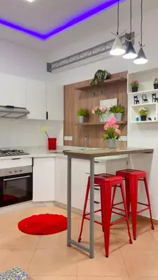a kitchen with a table and two red stools at Elégance & Confort in Rabat