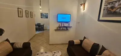 a living room with a couch and a tv on a wall at Jolie appartement calme à louer par jour in Bouznika