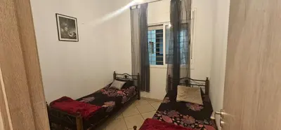 two beds in a small room with a window at Jolie appartement calme à louer par jour in Bouznika