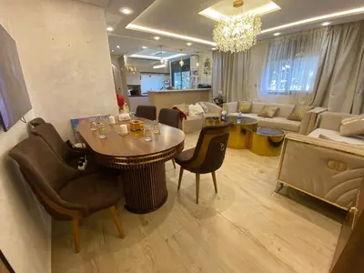 a living room with a table and chairs and a couch at Apartement charmante amira in Oulad Kerroum