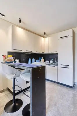 a kitchen with white cabinets and a counter with stools at Blue in Maarif