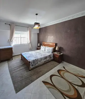 a bedroom with a bed and a large window at Appartement Rabat in Rabat