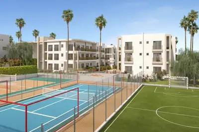 a tennis court in front of a building with palm trees at Appartement en bord de mer, Accès Plage & Parking in Mansouria