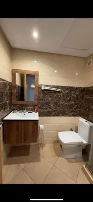a bathroom with a toilet and a sink and a mirror at Appartement de haut standing à EL MANSOURIA residence EBLA in Pont Blondin
