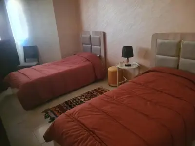 two beds in a room with red sheets at Régina AppartHotel in Casablanca