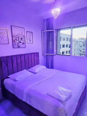 a purple bedroom with a large bed with a window at CHIC Studio - Appartements proche du Arribat Center AGDAL in Rabat