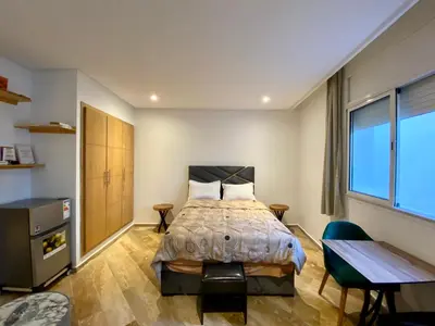 a bedroom with a bed and a desk and a window at Social apartment in Rabat