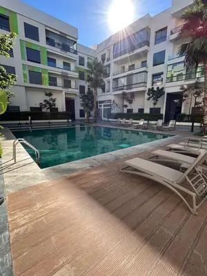 a swimming pool with lounge chairs and a building at Résidence Natura Living in Mohammedia