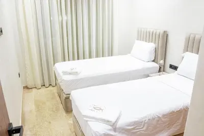 two beds in a room with white sheets at Dar Bouazza Luxury apartment with pools garden sports courts parking near the sea in Dar Bouazza
