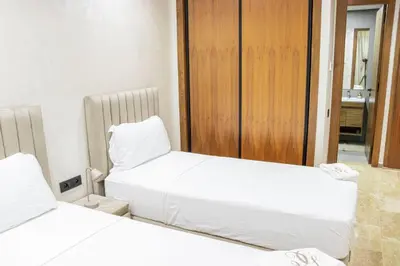 two beds in a small room with white sheets at Dar Bouazza Luxury apartment with pools garden sports courts parking near the sea in Dar Bouazza