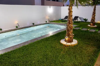 a swimming pool with a palm tree next to a building at Dar Bouazza Luxury apartment with pools garden sports courts parking near the sea in Dar Bouazza