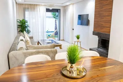 a living room with a table and a couch at Dar Bouazza Luxury apartment with pools garden sports courts parking near the sea in Dar Bouazza