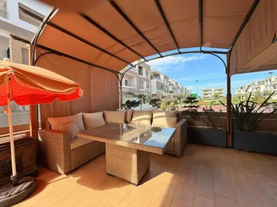 a patio with a table and chairs and an umbrella at Appartement Premium 3 Chambres Piscine et Accès Plage Mansouria in O Ben Slimane