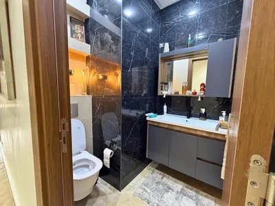 a bathroom with a toilet and a sink and a mirror at Appartement Premium 3 Chambres Piscine et Accès Plage Mansouria in O Ben Slimane