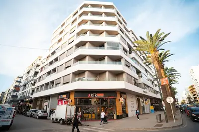 a tall white building with a palm tree in front of it at Skyline View Luxury Private Parking - Netflix in Casablanca