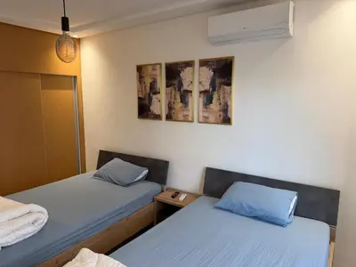 two beds in a room with blue pillows at Superbe appartement 120 mc, Plage à pieds, 3 piscines & calme garanti - Sidi Rahal Plage in Sidi Rahal