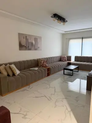 a living room with a couch and a table at Superbe appartement 120 mc, Plage à pieds, 3 piscines & calme garanti - Sidi Rahal Plage in Sidi Rahal