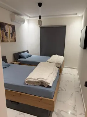 two twin beds in a room with a tv at Superbe appartement 120 mc, Plage à pieds, 3 piscines & calme garanti - Sidi Rahal Plage in Sidi Rahal