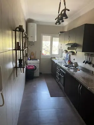 a kitchen with a sink and a stove top oven at Bel appartement in O Ben Slimane