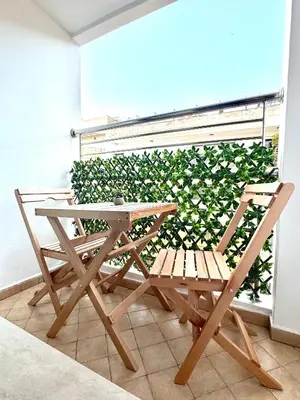 a table and chairs next to a green wall at CityZen Suites, Luxury 3BR near Mohamed V Stadium in Maarif