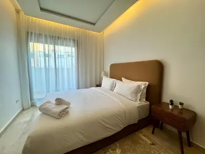 a bedroom with a large bed with a window at CityZen Suites, Luxury 3BR near Mohamed V Stadium in Maarif